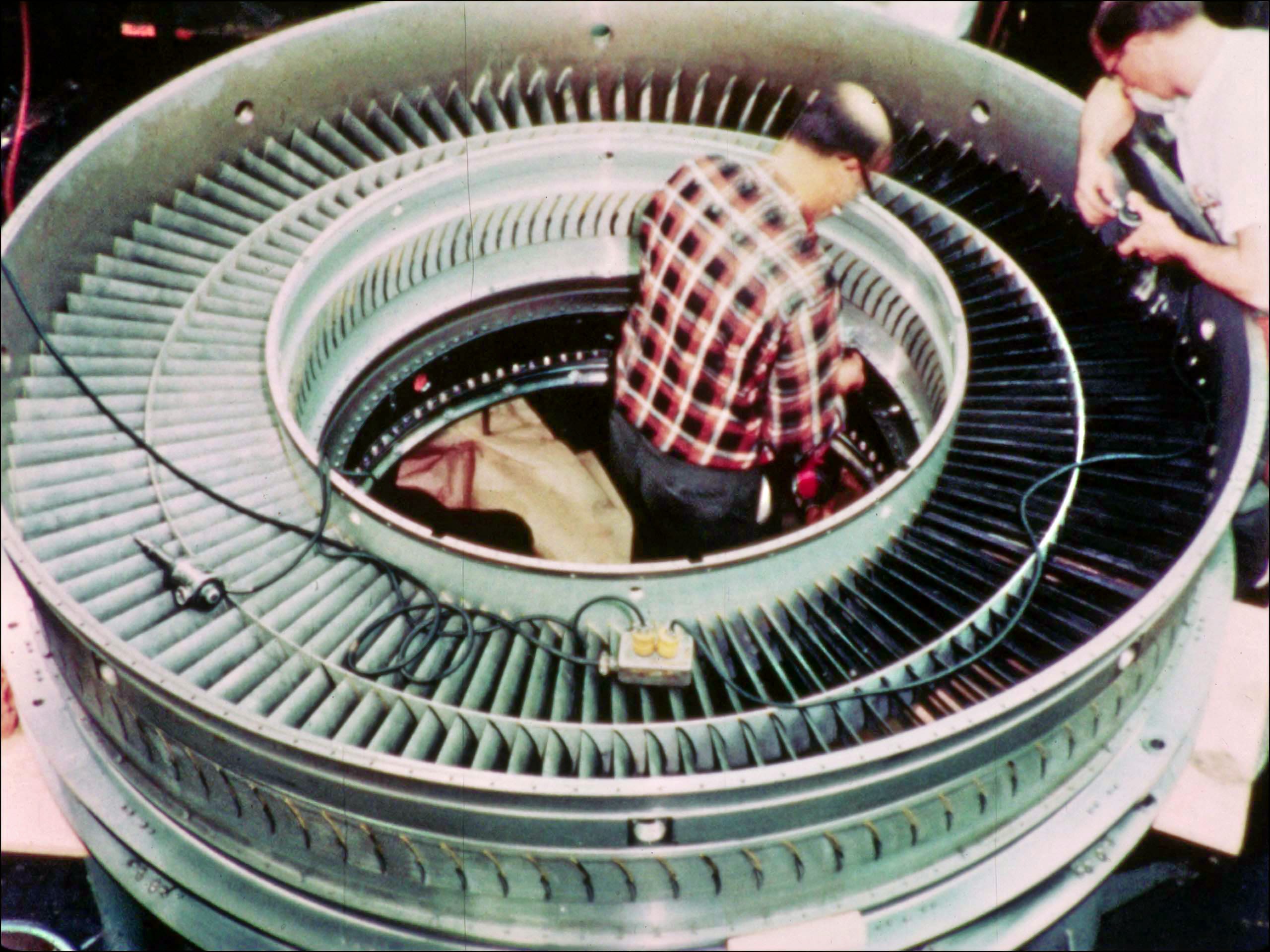 Frame showing workers in a partially assembed Pratt & Whitney JTD9 engine from "The Superjet" (Pan Am Historical Foundation Film Collection).