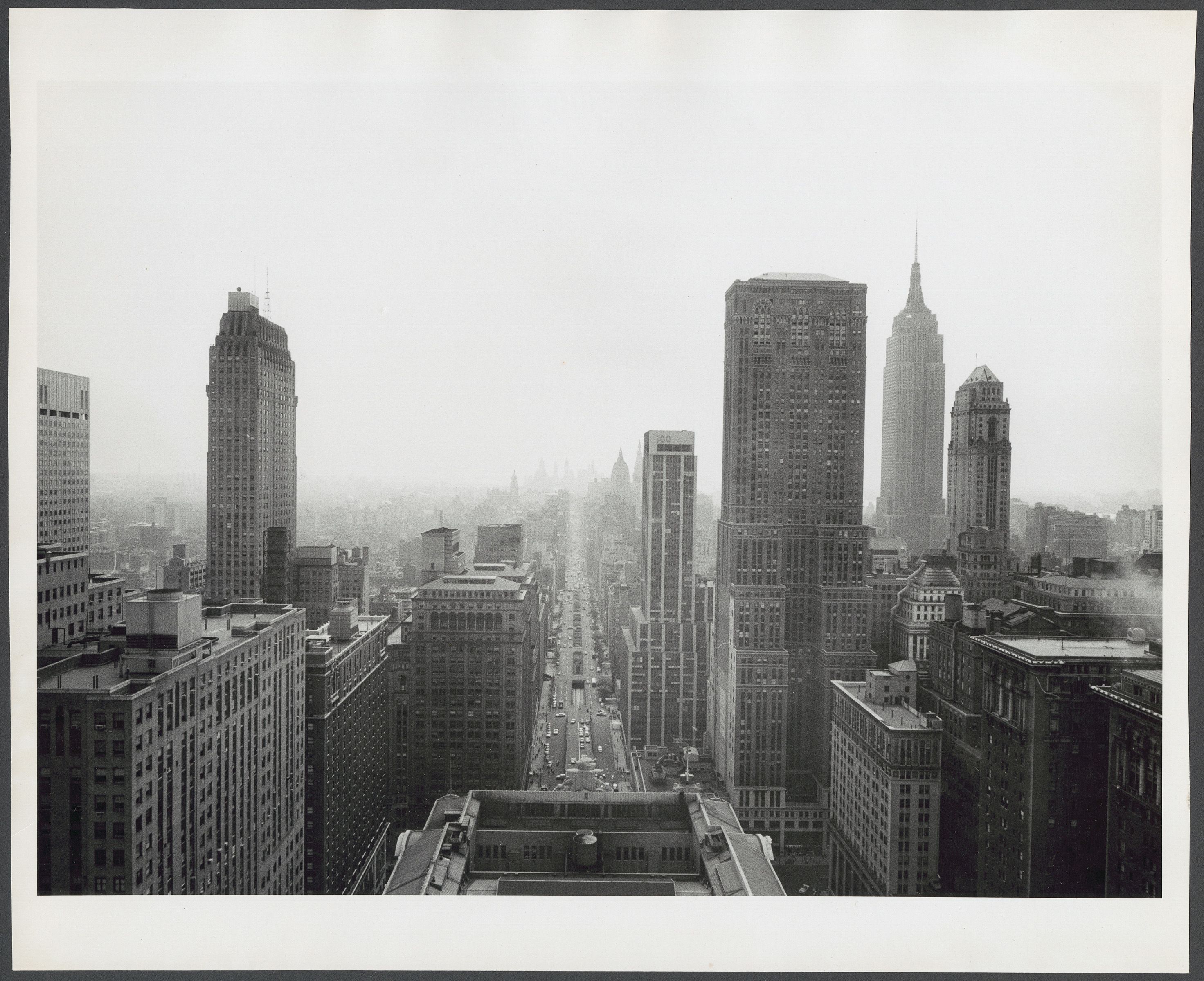 Photograph shows bird's eye view of Grand Central Terminal and Park Avenue. One Grand Central Place, the Mercantile Building, and the Empire State Building are visible to the right.
